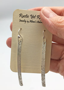 super skinny earrings shown on card and held in hand