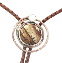 Load image into Gallery viewer, Bolo tie with brown leather strap and metallic circular design on a white background