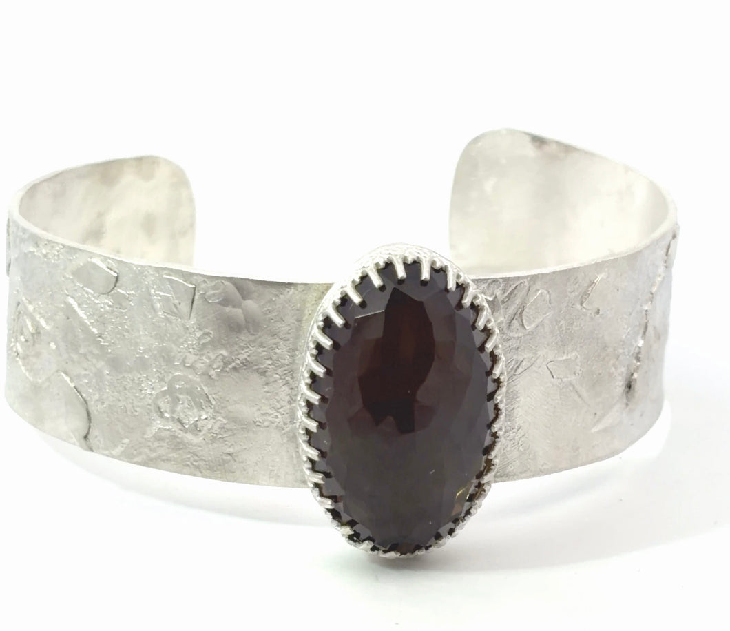 Silver cuff bracelet with a dark stone on a white background