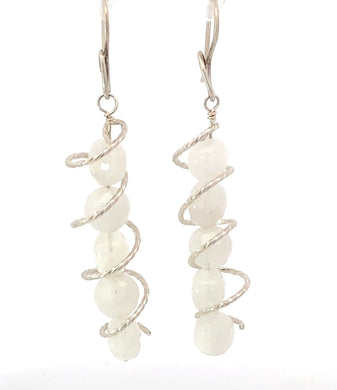 Pair of earrings with white beads and silver wire spiral design on a white background