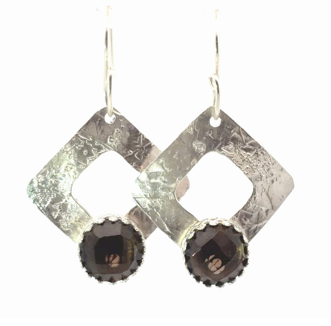 Diamond-shaped earrings with dark gemstones on a white background