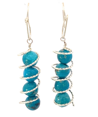 Handmade turquoise spiral earrings in sterling silver, featuring vibrant turquoise beads and elegant design.