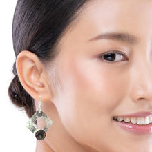 Load image into Gallery viewer, Close-up of a woman wearing a silver earring with a dark gemstone on a white background