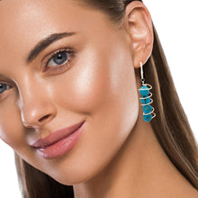 Load image into Gallery viewer, Model wearing turquoise spiral sterling silver earrings, showcasing the elegant design with vibrant turquoise stones.
