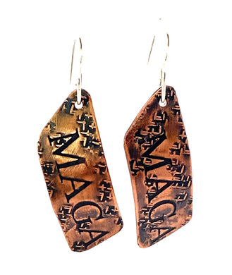 Pair of copper earrings with 'MAGA' engraving on a white background