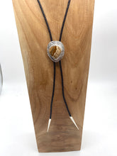 Load image into Gallery viewer, Bolo tie with a decorative clasp on a wooden block against a white background