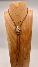 Load image into Gallery viewer, Necklace with a circular pendant on a wooden stand against a white background