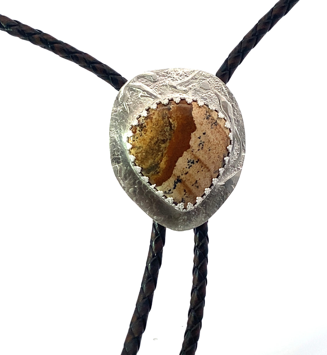 Bolo tie with a textured stone and silver design on a white background