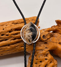 Load image into Gallery viewer, Bolo Tie with a circular pendant on black cord over wooden driftwood
