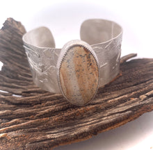 Load image into Gallery viewer, Silver cuff bracelet with a stone inlay on a wooden surface