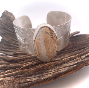 Silver cuff bracelet with a stone inlay on a wooden surface
