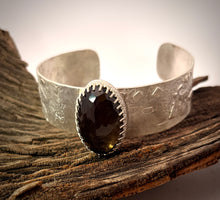 Load image into Gallery viewer, Silver cuff bracelet with a dark gemstone on a wooden surface