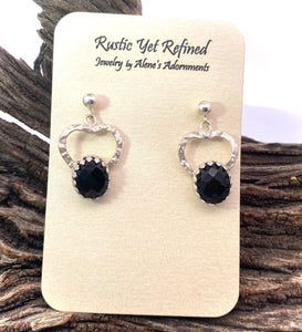 Pair of silver earrings with black stones on a rustic wooden background