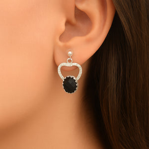 Earring with black gemstone and silver setting worn on an ear