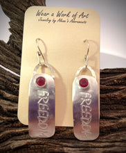 Load image into Gallery viewer, Silver FREEDOM earrings with ruby gems on a 'Wear a Work of Art' card, placed on wooden surface.