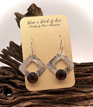 Load image into Gallery viewer, Silver earrings with dark gemstones on a wooden surface with a &#39;Wear a Work of Art&#39; card.