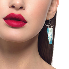 Load image into Gallery viewer, A close-up of a model's lower face, neck, and hair wearing a single dangling earring. The earring features sterling silver with cloud dreams design 
