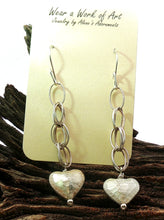 Load image into Gallery viewer, Silver hoop earrings with heart pendants on a card, placed on wooden branches.