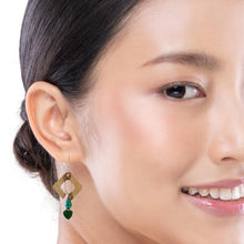 Load image into Gallery viewer, A close-up of a woman's ear and side profile wearing a dangling earring with a gold diamond-shaped frame and green malachite heart-shaped gems