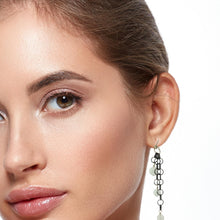 Load image into Gallery viewer, A close-up of a woman's face and ear wearing a long dangling earring with black circular links and faceted moonstone beads