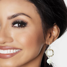 Load image into Gallery viewer, A close-up of a woman's face wearing a dangling earring with a silver square frame, a white moonstones 