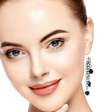 Load image into Gallery viewer, A close-up portrait of a woman with smooth skin and subtle makeup, wearing a long dangling earring with black heart-shaped onyx beads, against a clean white background.