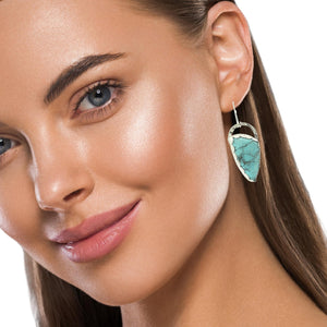 Close-up of a woman wearing a turquoise earring on a white background