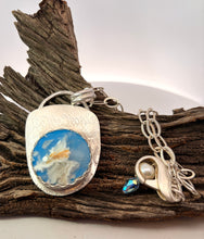 Load image into Gallery viewer, Silver pendant with a blue and white design on a piece of wood