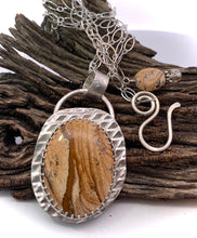 Load image into Gallery viewer, Necklace with a pendant featuring a brown stone and silver setting on a wooden background