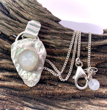 Load image into Gallery viewer, Silver pendant with a white stone on a wooden surface