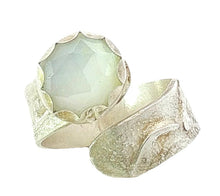 Load image into Gallery viewer, A textured silver ring featuring a large, faceted, moonstone, 