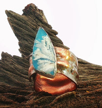 Load image into Gallery viewer, A handmade ring featuring a large, teardrop-shaped plume agate gem embedded white clouds, set in a rustic copper and silver band, displayed on a piece of weathered wood.